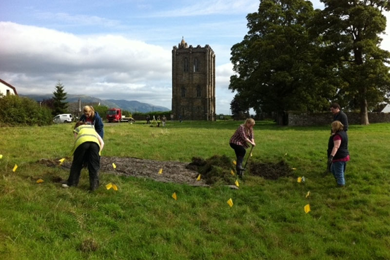 Volunteers breaking ground in the shadow of the abbey tower.